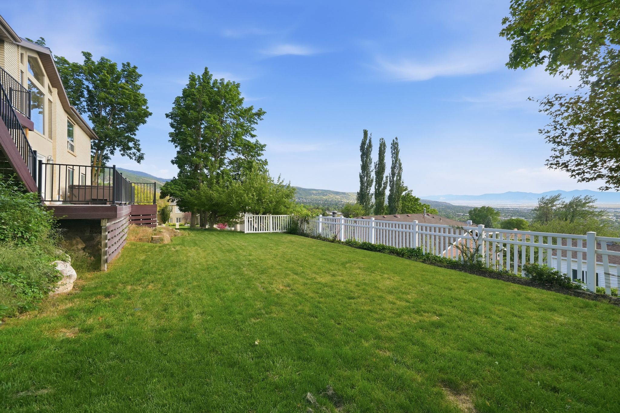 Expansive lawn area with a white picket fence bordering the property