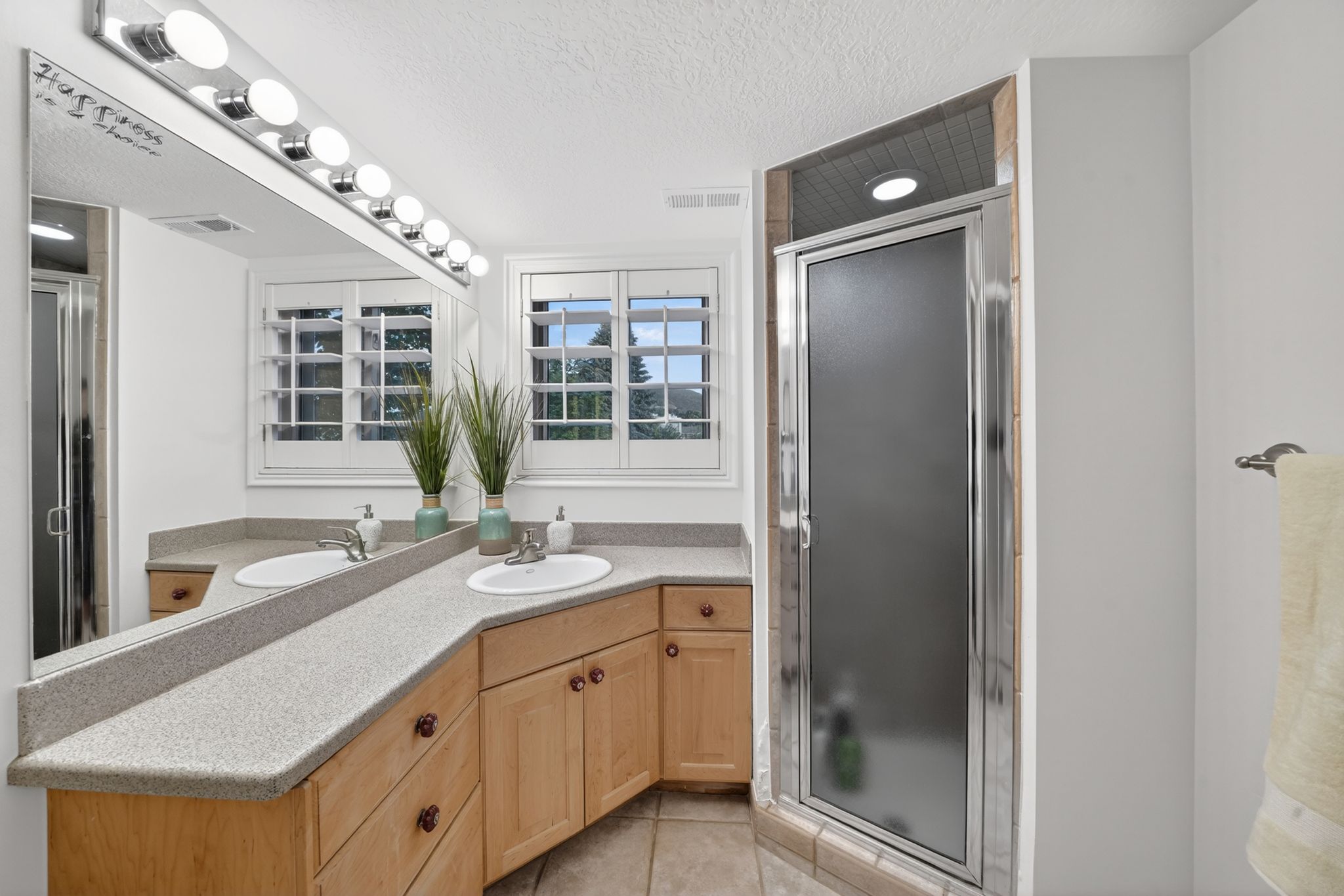 Bathroom featuring an extended vanity with dual undermount sinks and light-toned countertops