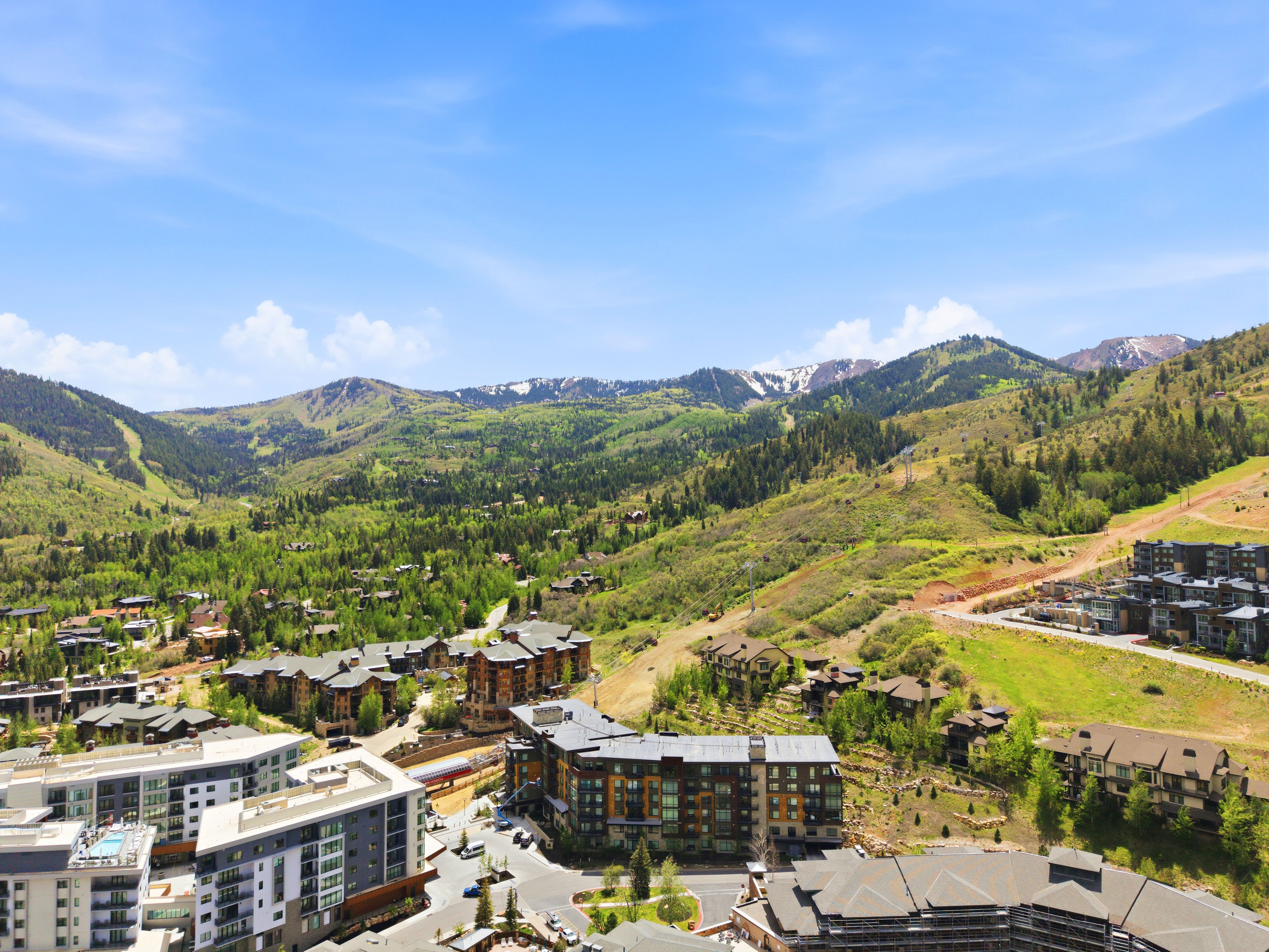 Expansive mountain and valley scenery featuring distant snow-capped peaks and forested slopes