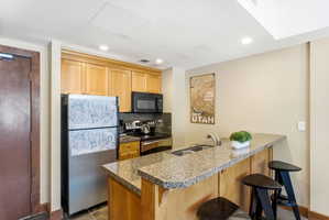 Kitchen featuring granite countertops, stainless steel appliances, wood cabinetry, and recessed lighting