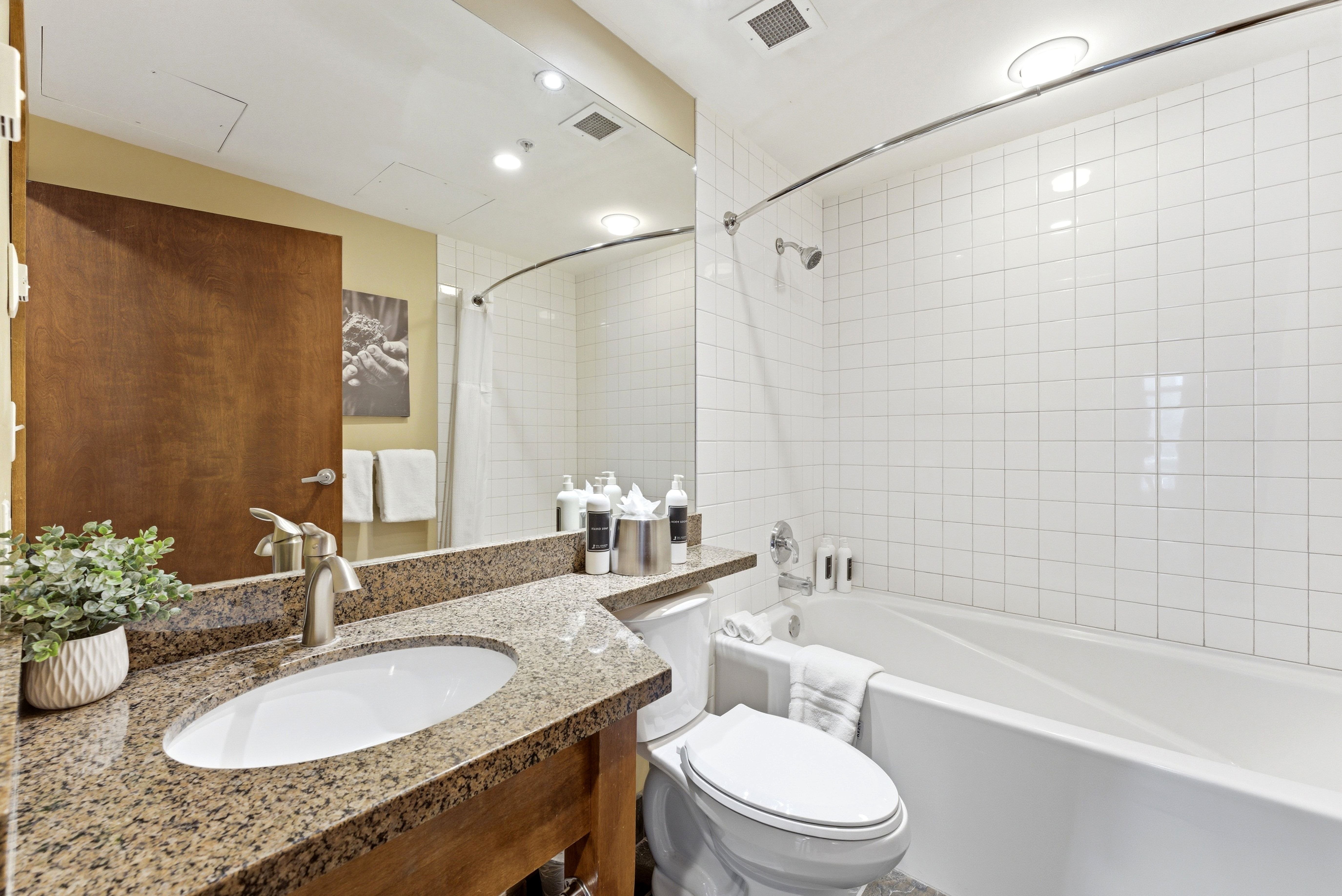 Bathroom featuring a single vanity with a granite countertop, undermount sink, and brushed nickel faucet