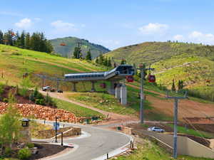 Mountain terrain with a ski lift infrastructure, red gondola cabins, and a paved road