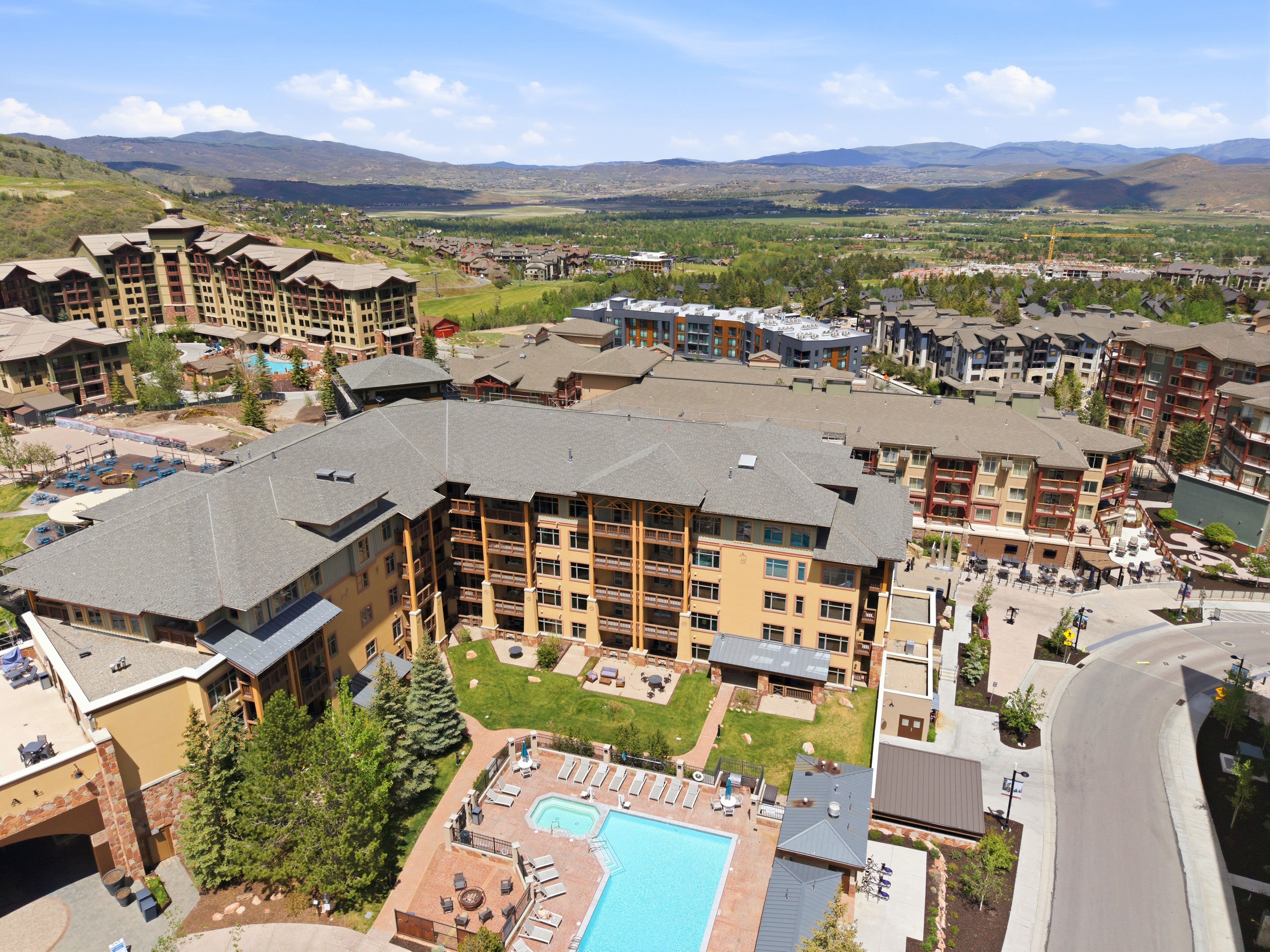 Contemporary multi-story building featuring multiple balconies, a ground-level swimming pool, and a spa