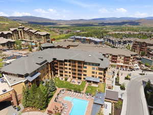 Contemporary multi-story building featuring multiple balconies, a ground-level swimming pool, and a spa