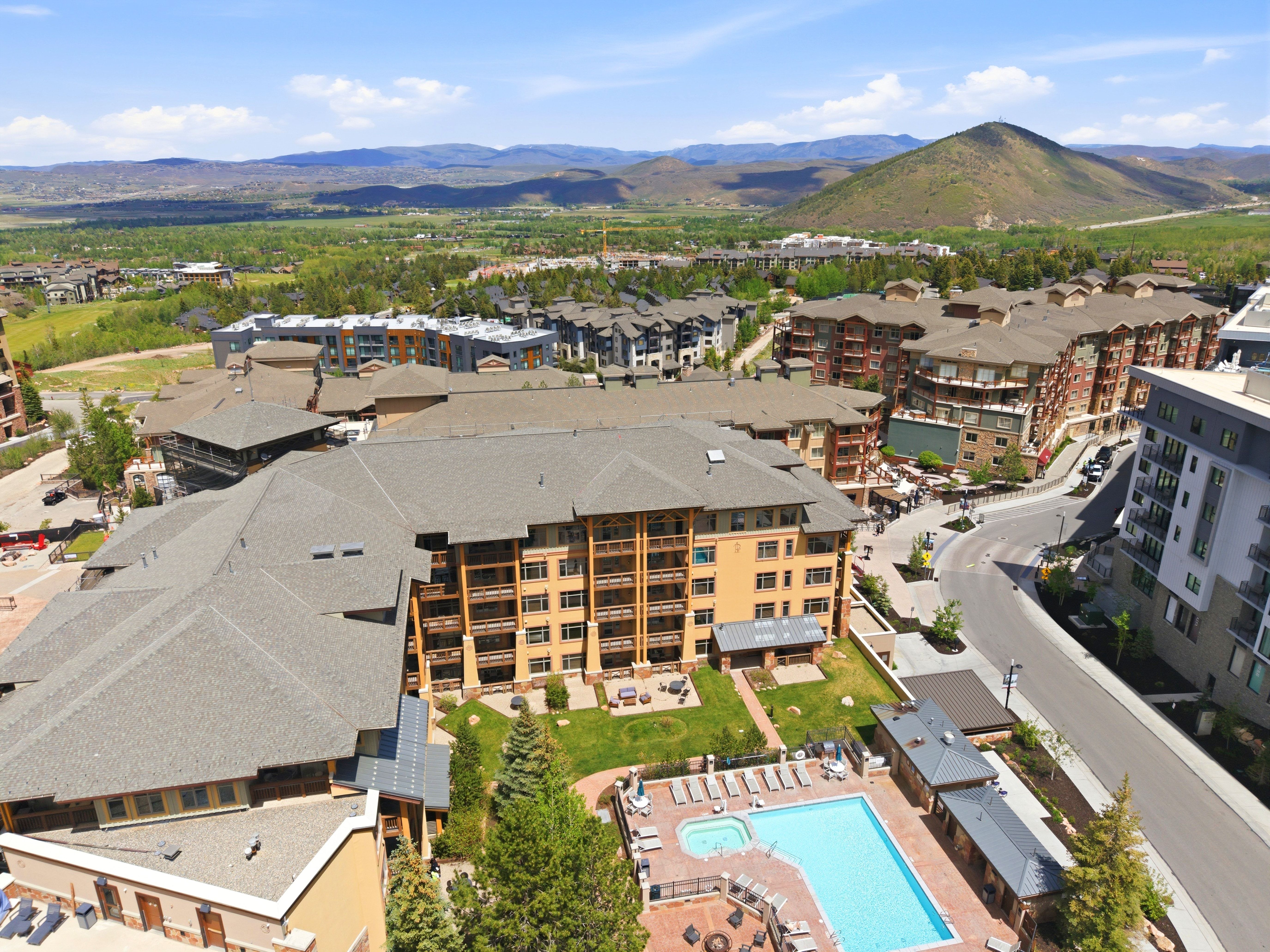 Expansive community featuring multi-story residential buildings with balconies, a central swimming pool, and a spa area