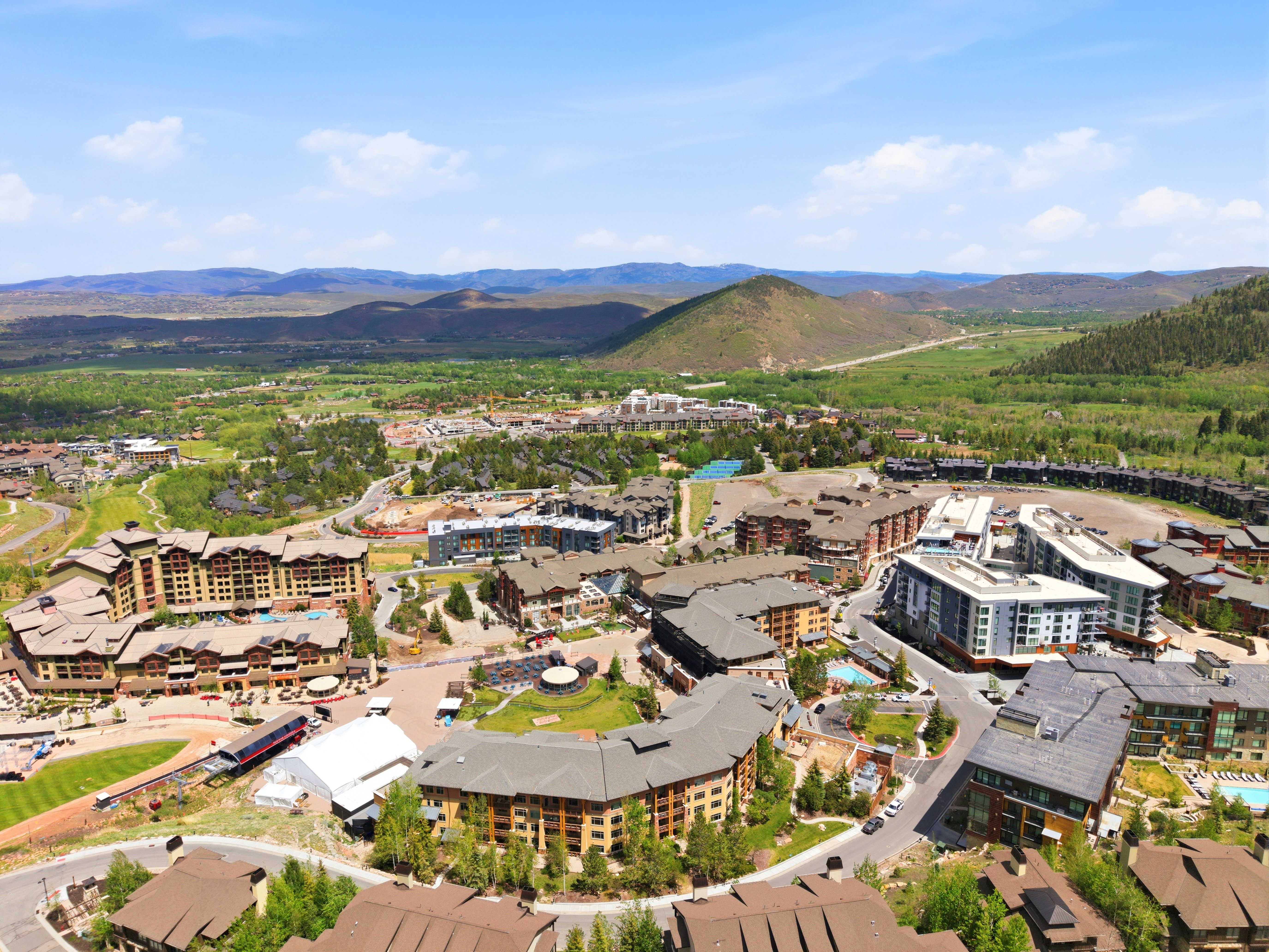 Expansive aerial perspective showcasing a vibrant community nestled within a mountainous, verdant landscape