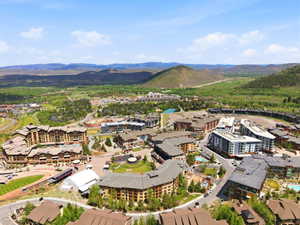 Expansive aerial perspective showcasing a vibrant community nestled within a mountainous, verdant landscape