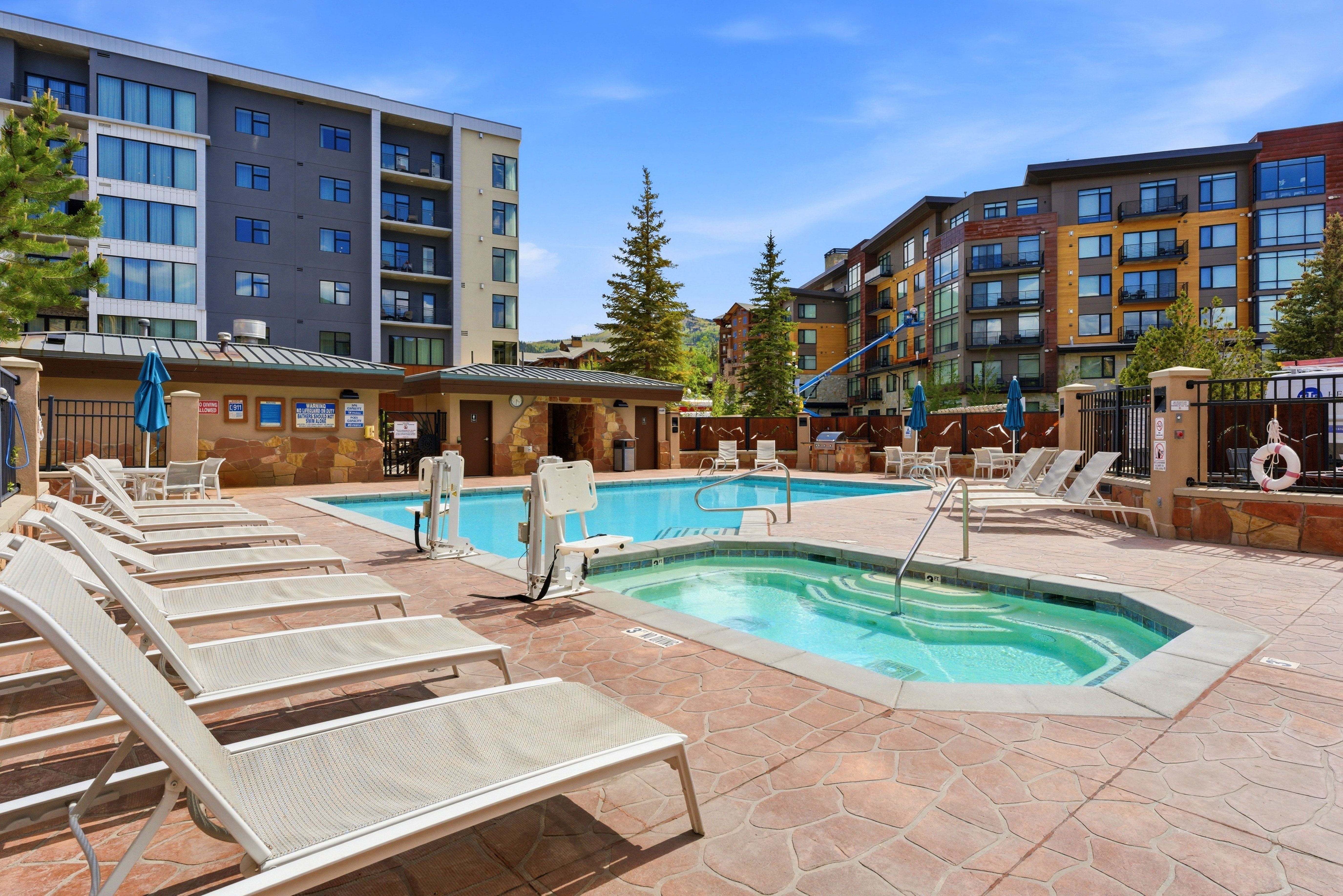 Outdoor pool area featuring a large swimming pool, an integrated hot tub, and an expansive stamped concrete deck