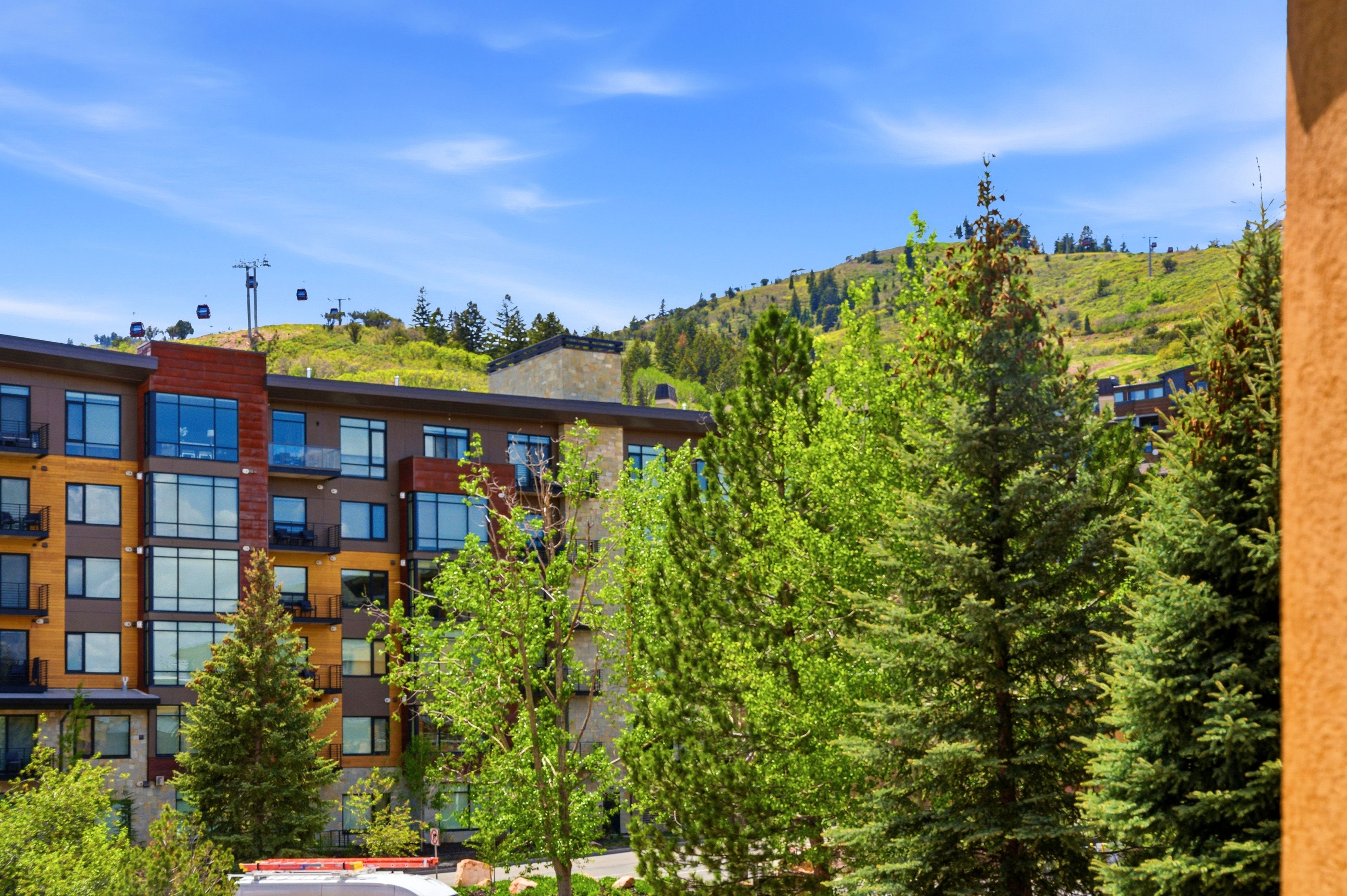 Multi-story building featuring wood-look siding, stone accents, and numerous balconies