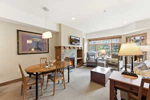 Open-concept living area featuring a stone-faced fireplace with wood mantel, large window array, recessed lighting, and a modern dining pendant light fixture