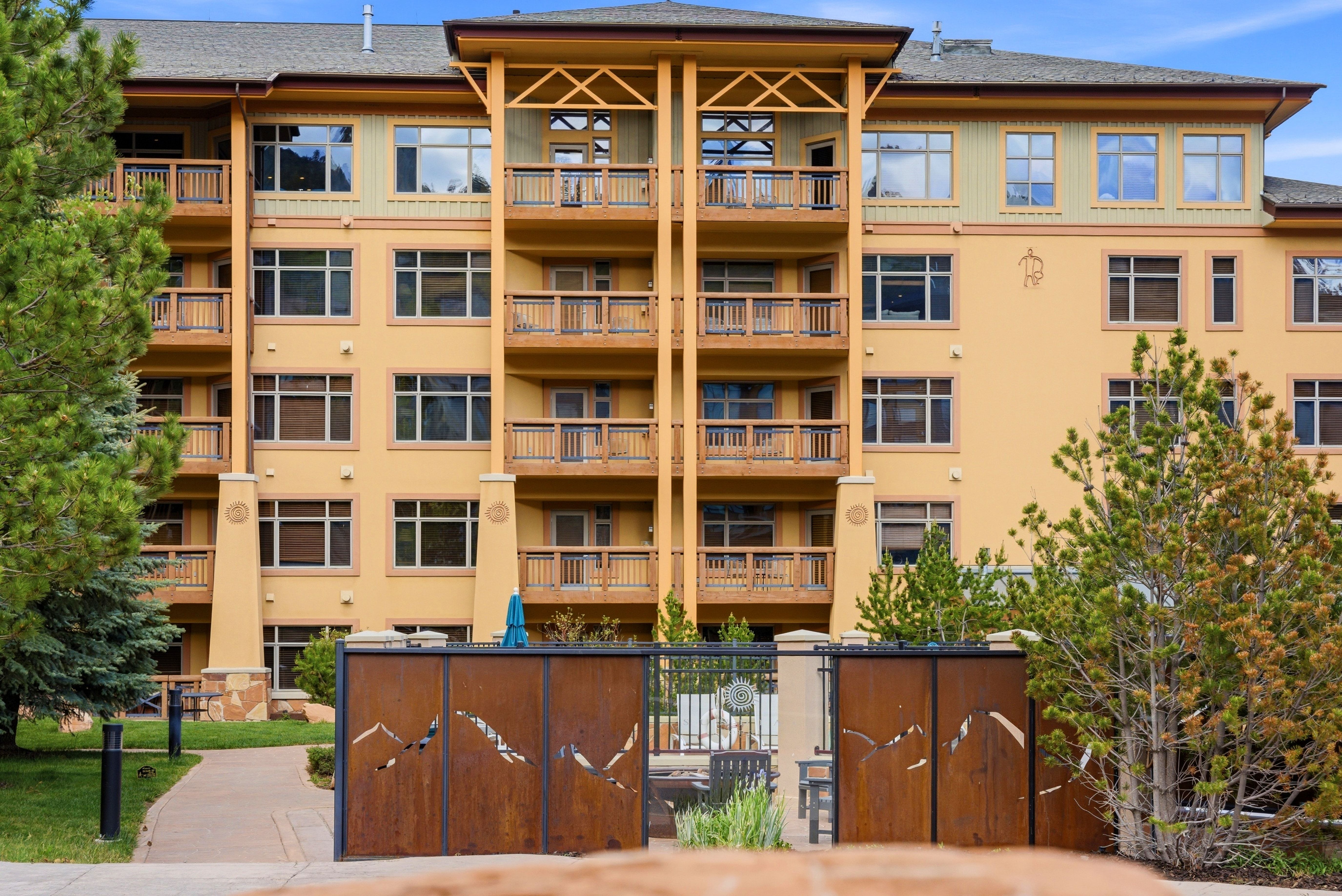 Multi-level architectural building featuring numerous private balconies with wood railings, a stucco exterior, and extensive windowing