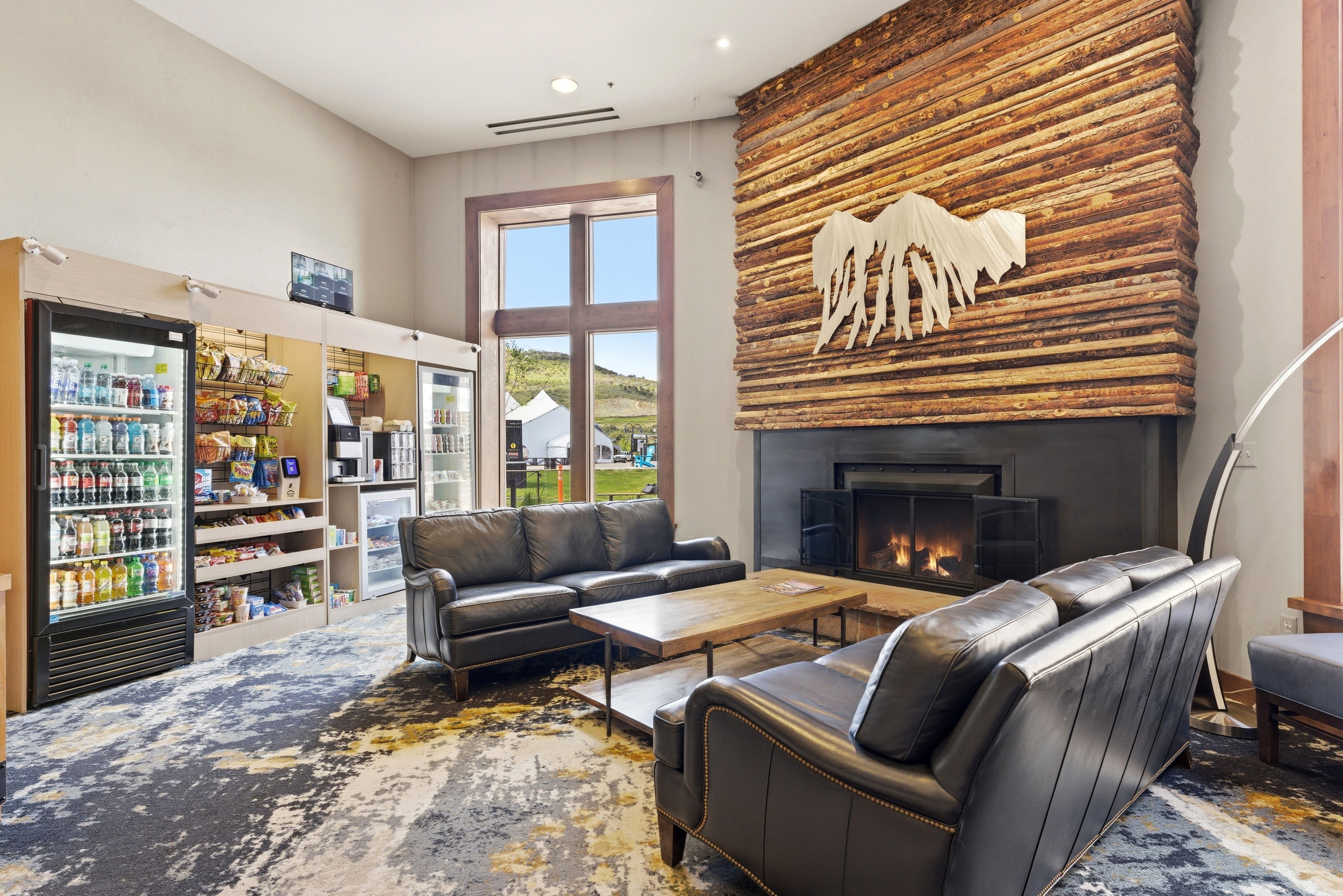 Spacious common area featuring a striking wood panel fireplace, high ceilings, large window with outdoor visibility, and a built-in refreshment station