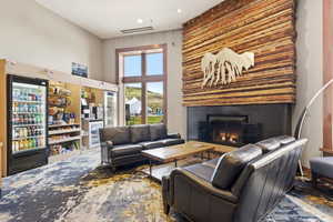 Spacious common area featuring a striking wood panel fireplace, high ceilings, large window with outdoor visibility, and a built-in refreshment station