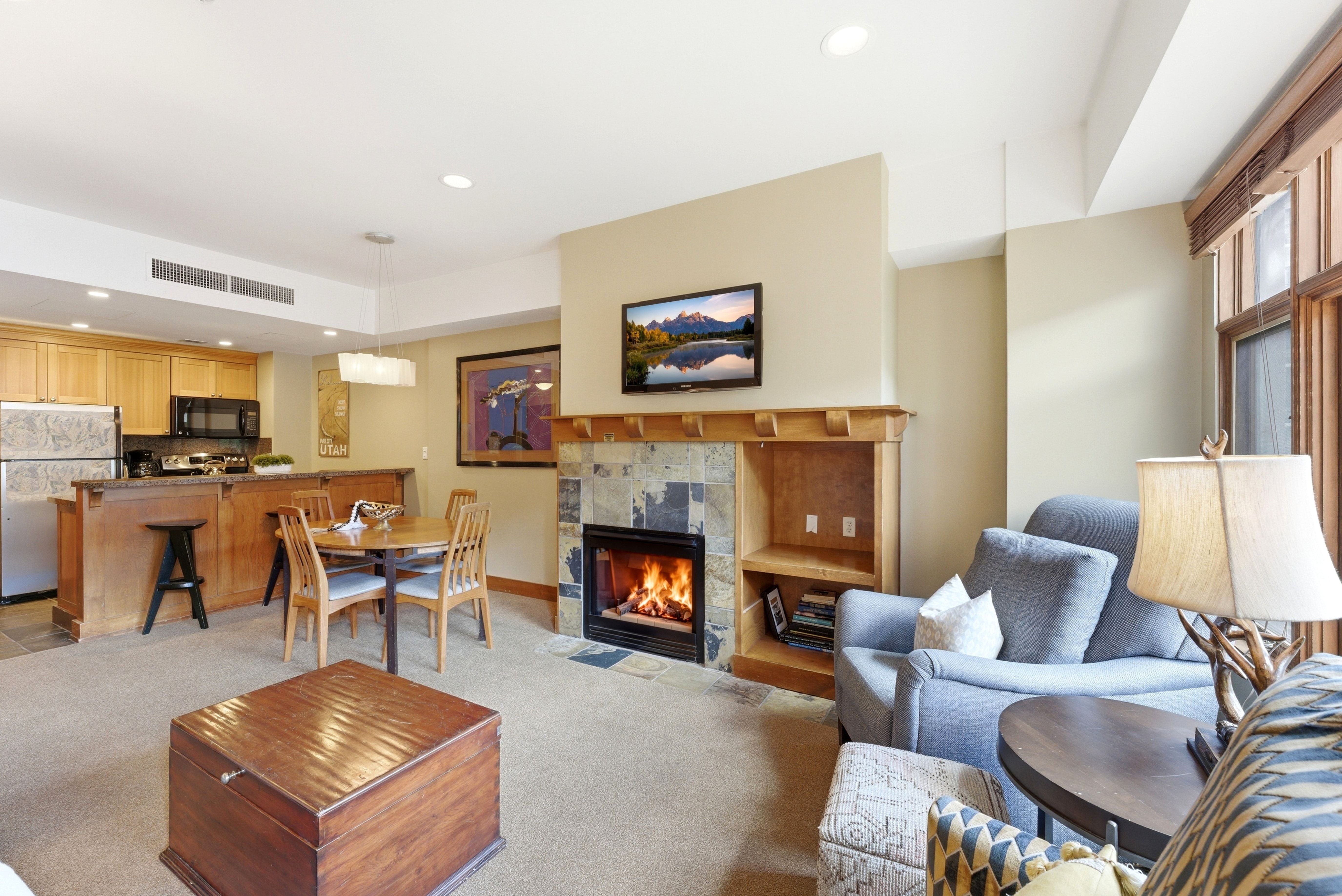 Living area featuring a stone-surround fireplace with a wood mantle, built-in shelving, and carpeted flooring