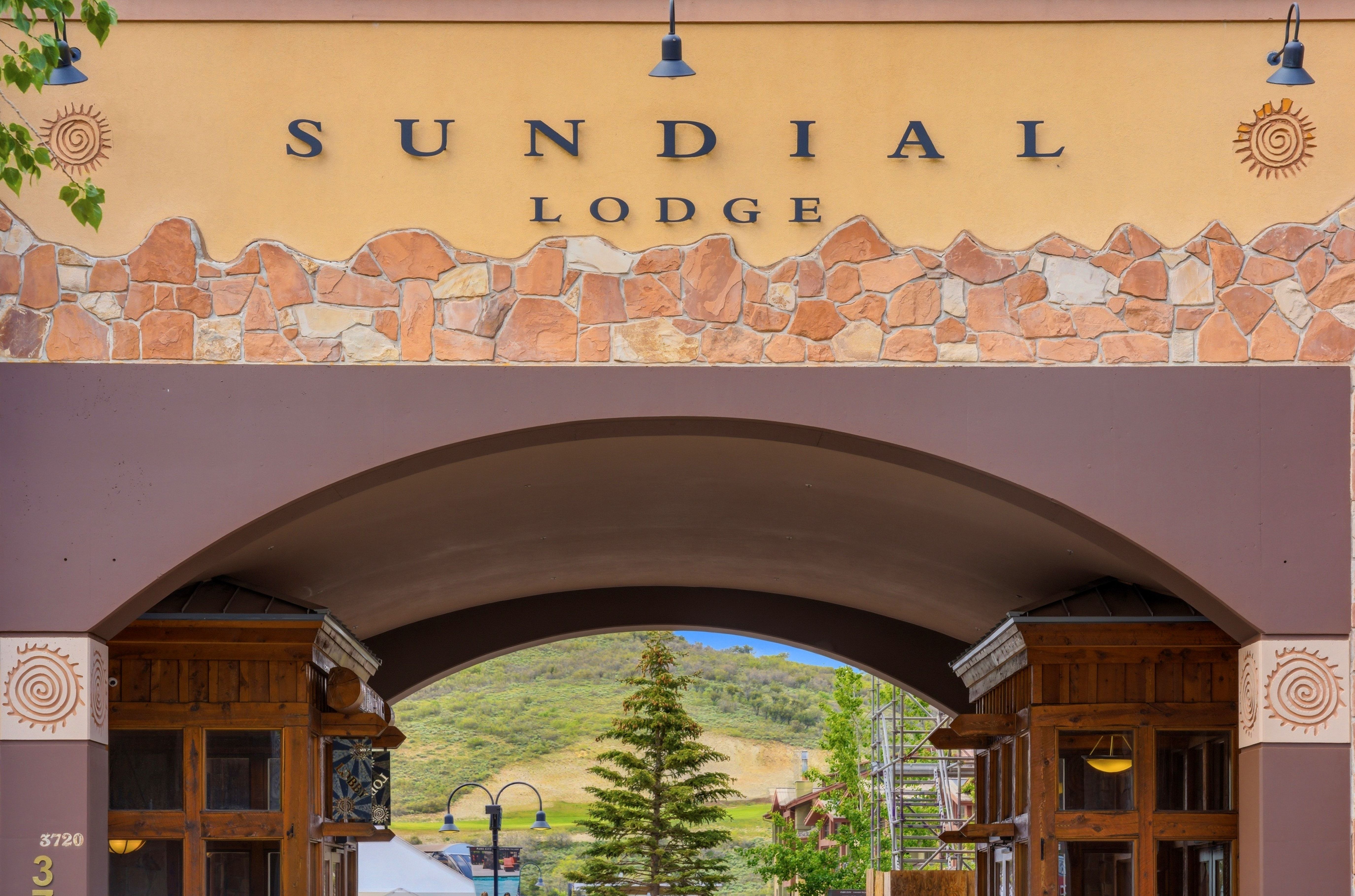 Archway entrance featuring a stone facade with integrated signage, decorative sconces, and carved wood architectural details