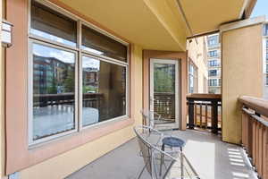 Private balcony with concrete flooring, stucco exterior, and a glass-paneled door