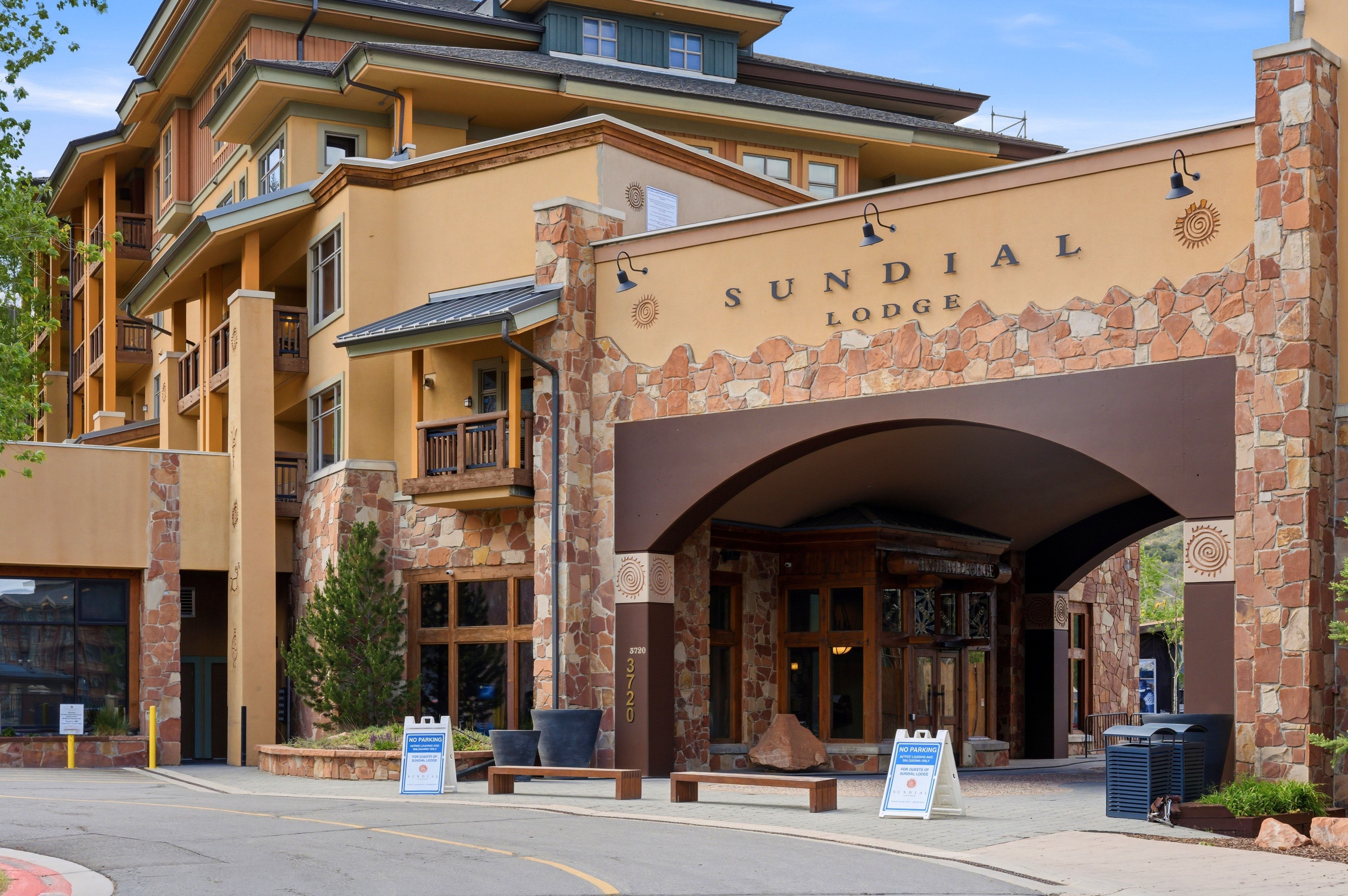 Sundial Lodge building entrance featuring stone and stucco facade, arched entryway, and multiple balconies with wood railings