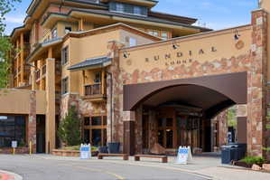 Sundial Lodge building entrance featuring stone and stucco facade, arched entryway, and multiple balconies with wood railings