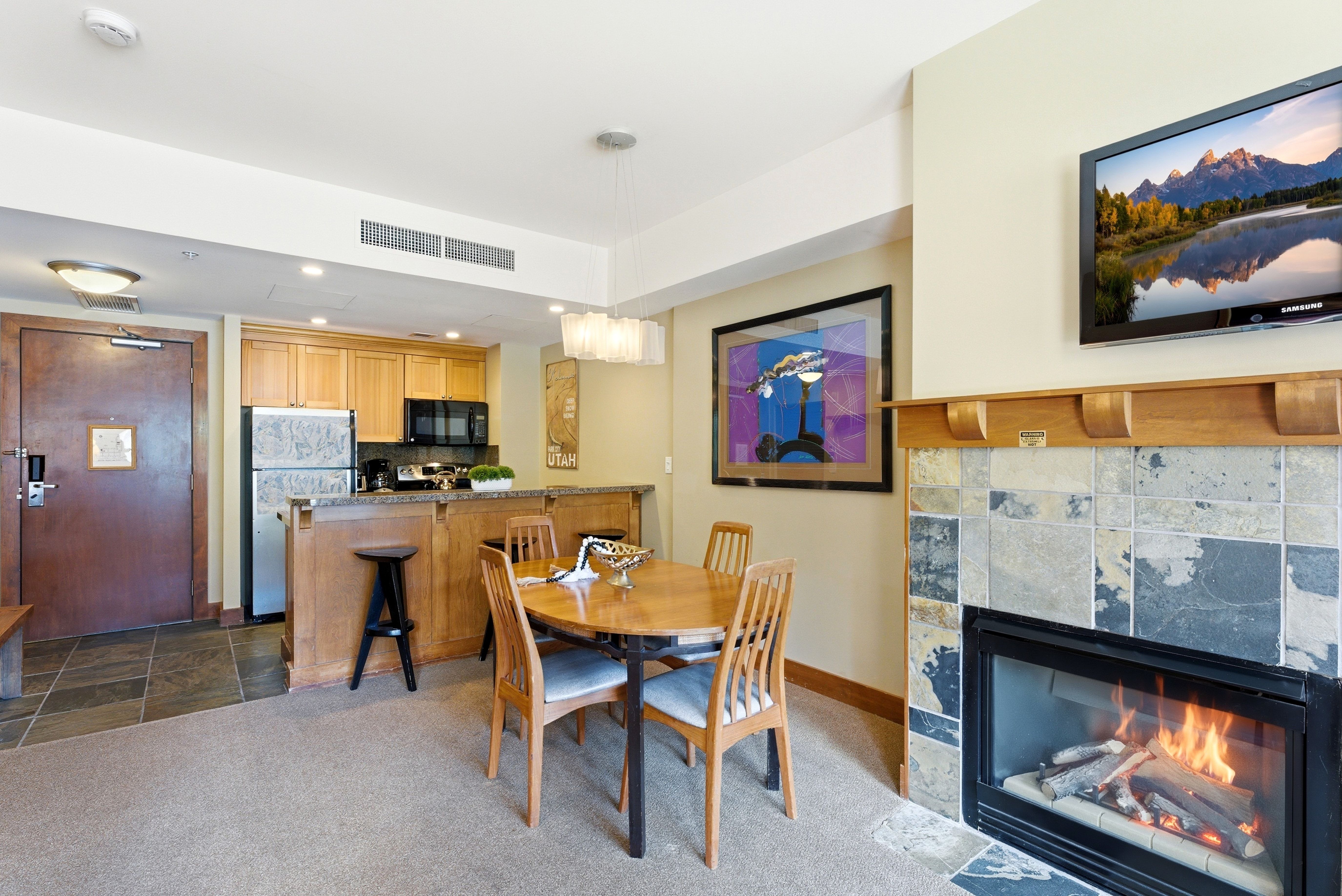 Cozy living area featuring a stone tile fireplace with a wood mantel, a flat-screen television mount, and carpet flooring