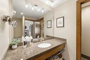 Vanity with a granite countertop, undermount sink, and brushed nickel faucet