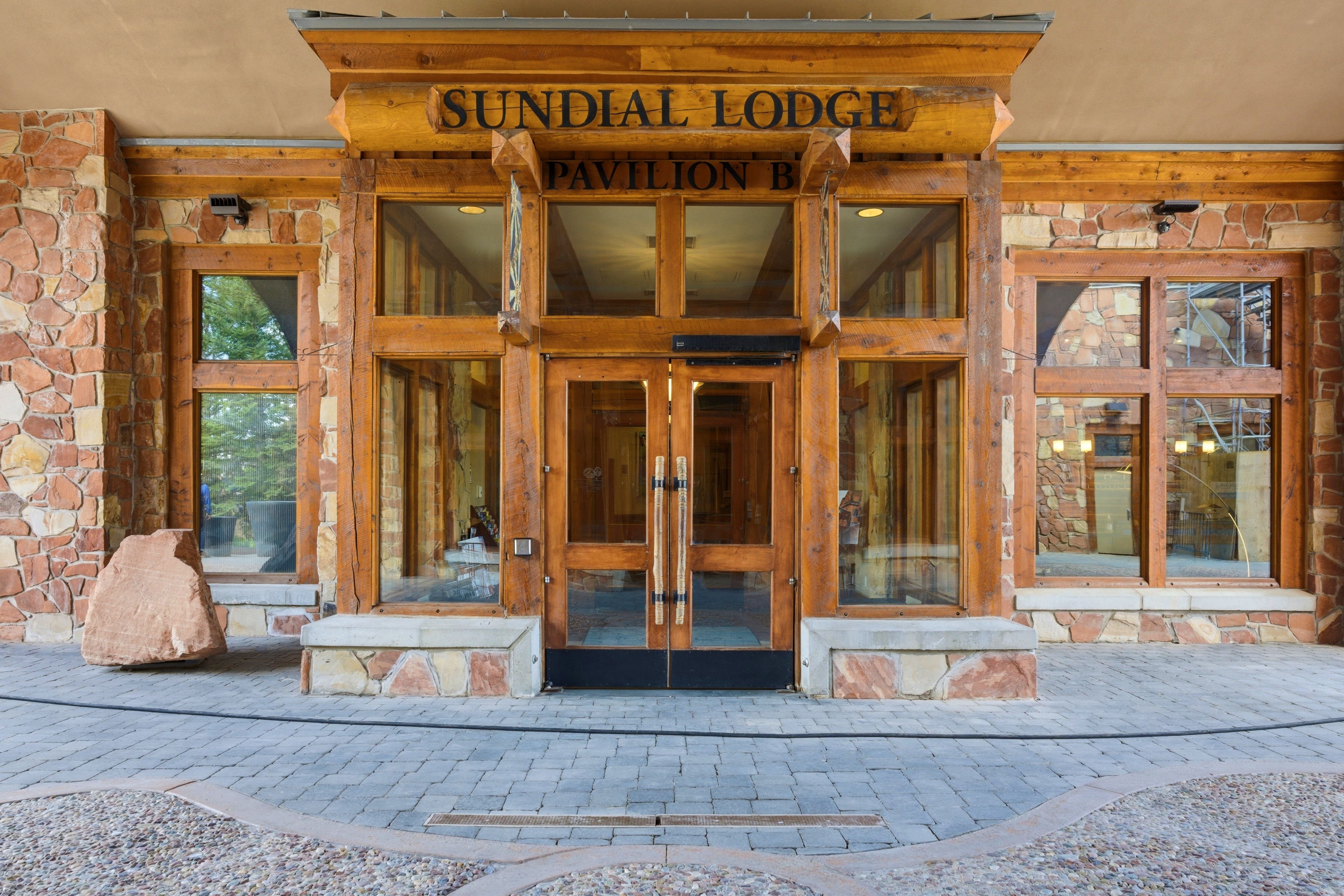 Stone facade with prominent wood beam accents and a central glass entry system