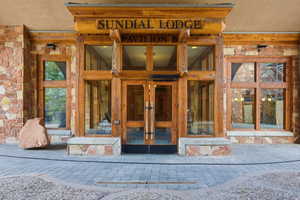 Stone facade with prominent wood beam accents and a central glass entry system