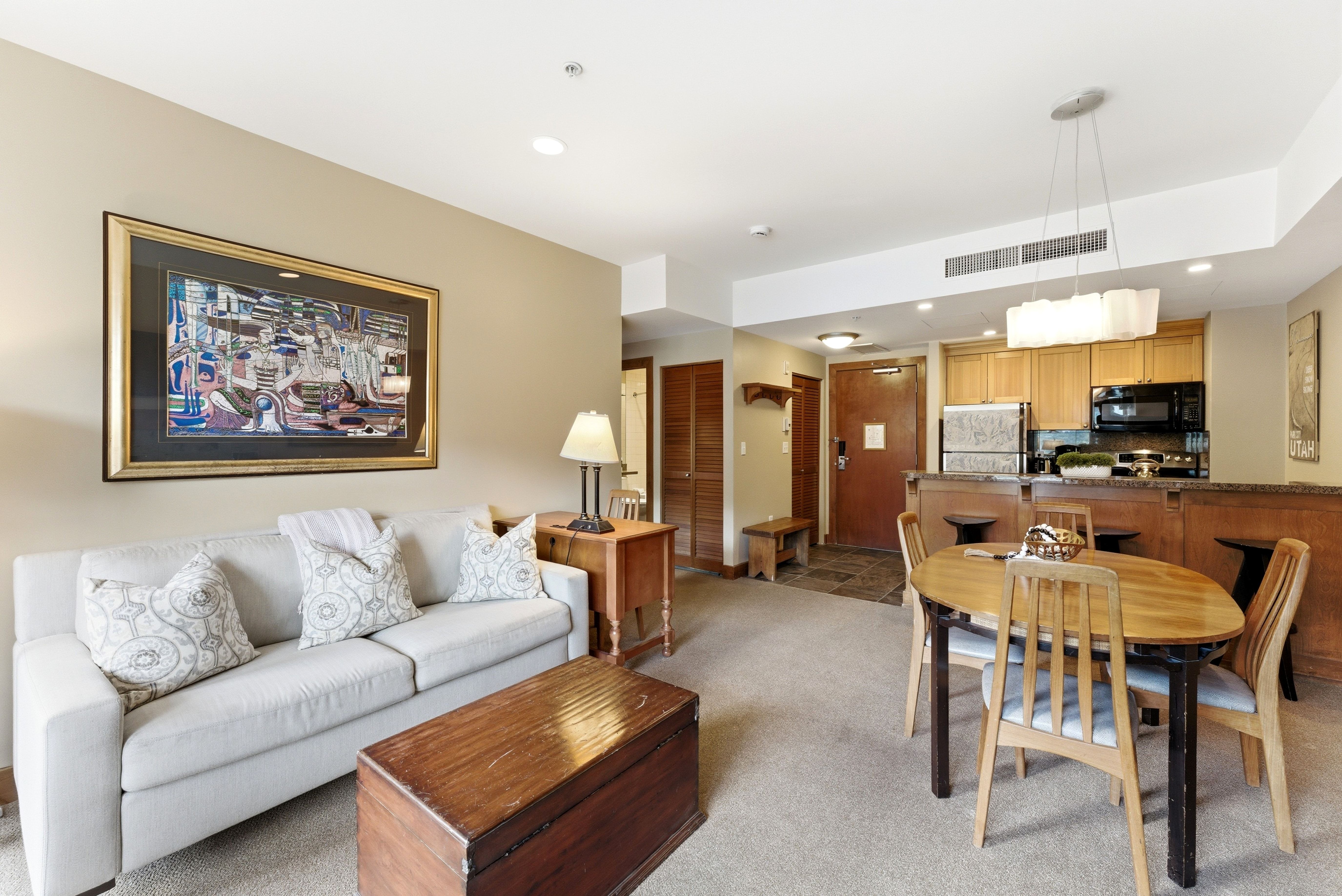 Open-concept living space featuring neutral carpet flooring, recessed lighting, and a kitchen with wood cabinetry and black appliances