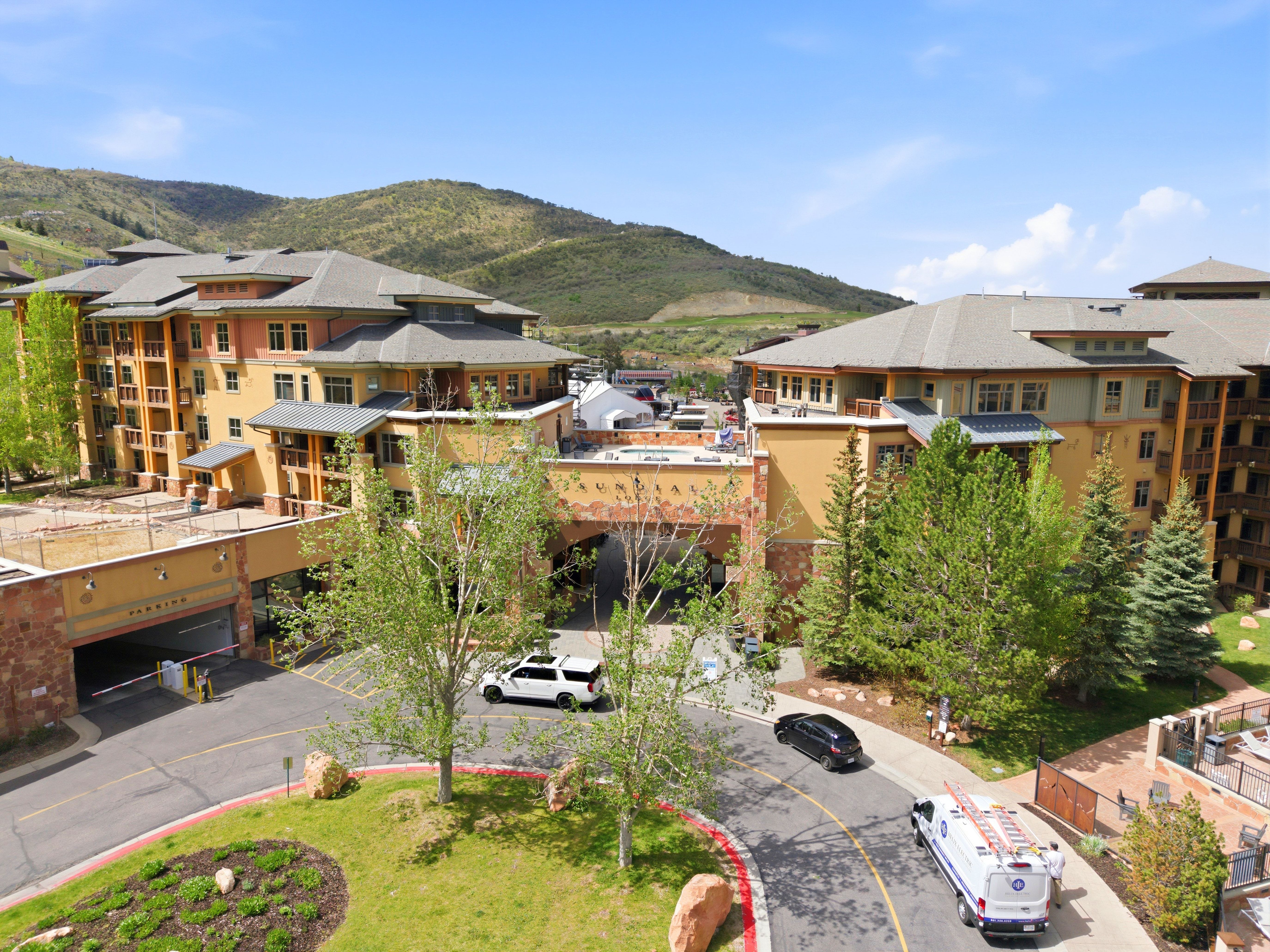 Multi-story residential complex featuring a tiered architectural design, multiple private balconies, a central arched entryway, and integrated parking access