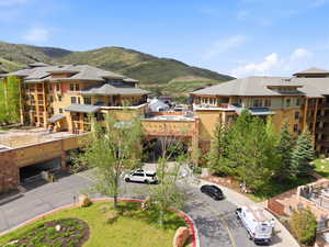 Multi-story residential complex featuring a tiered architectural design, multiple private balconies, a central arched entryway, and integrated parking access