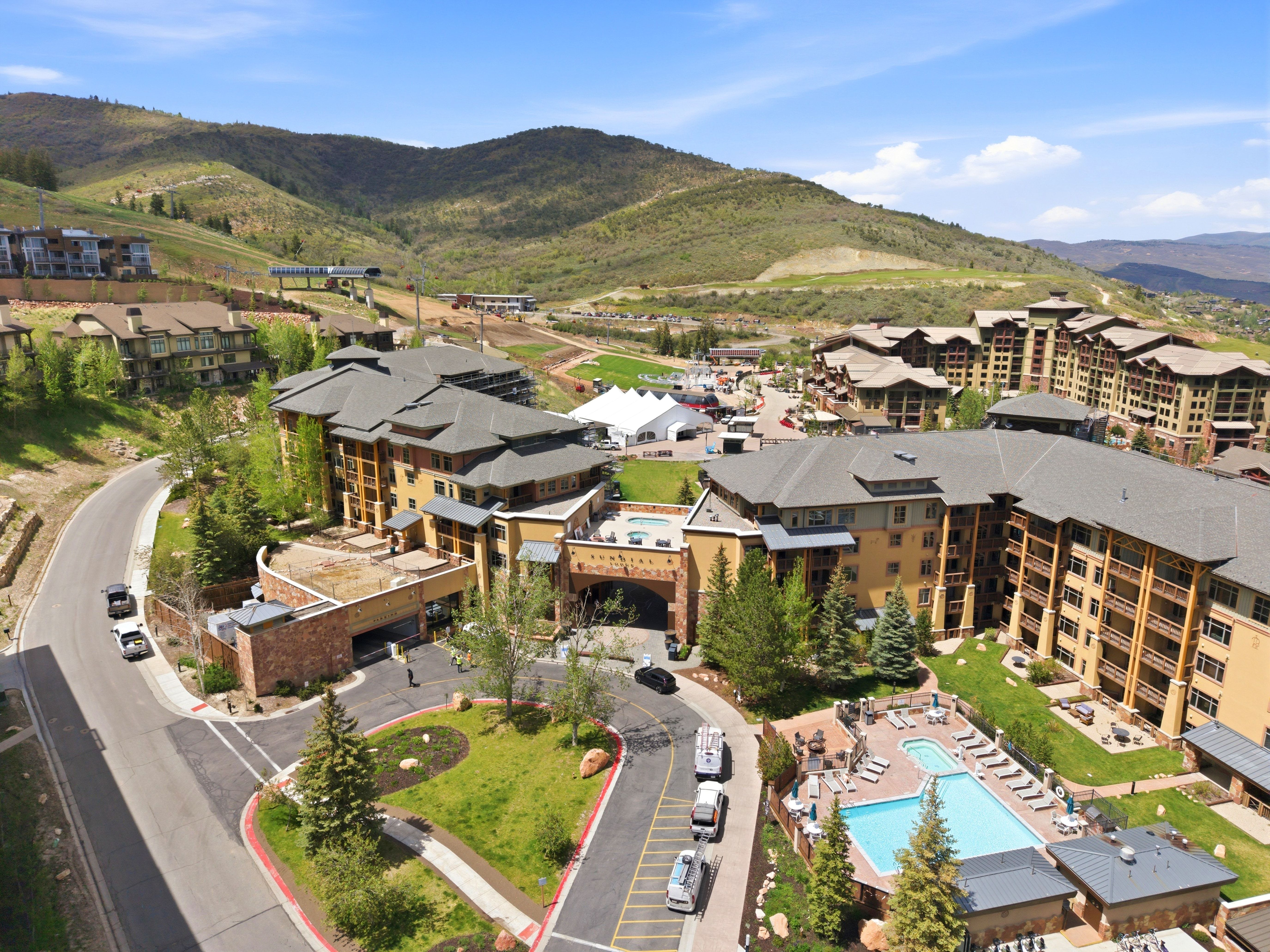 Resort-style property featuring multiple buildings with balconies, a swimming pool, and surrounding green spaces
