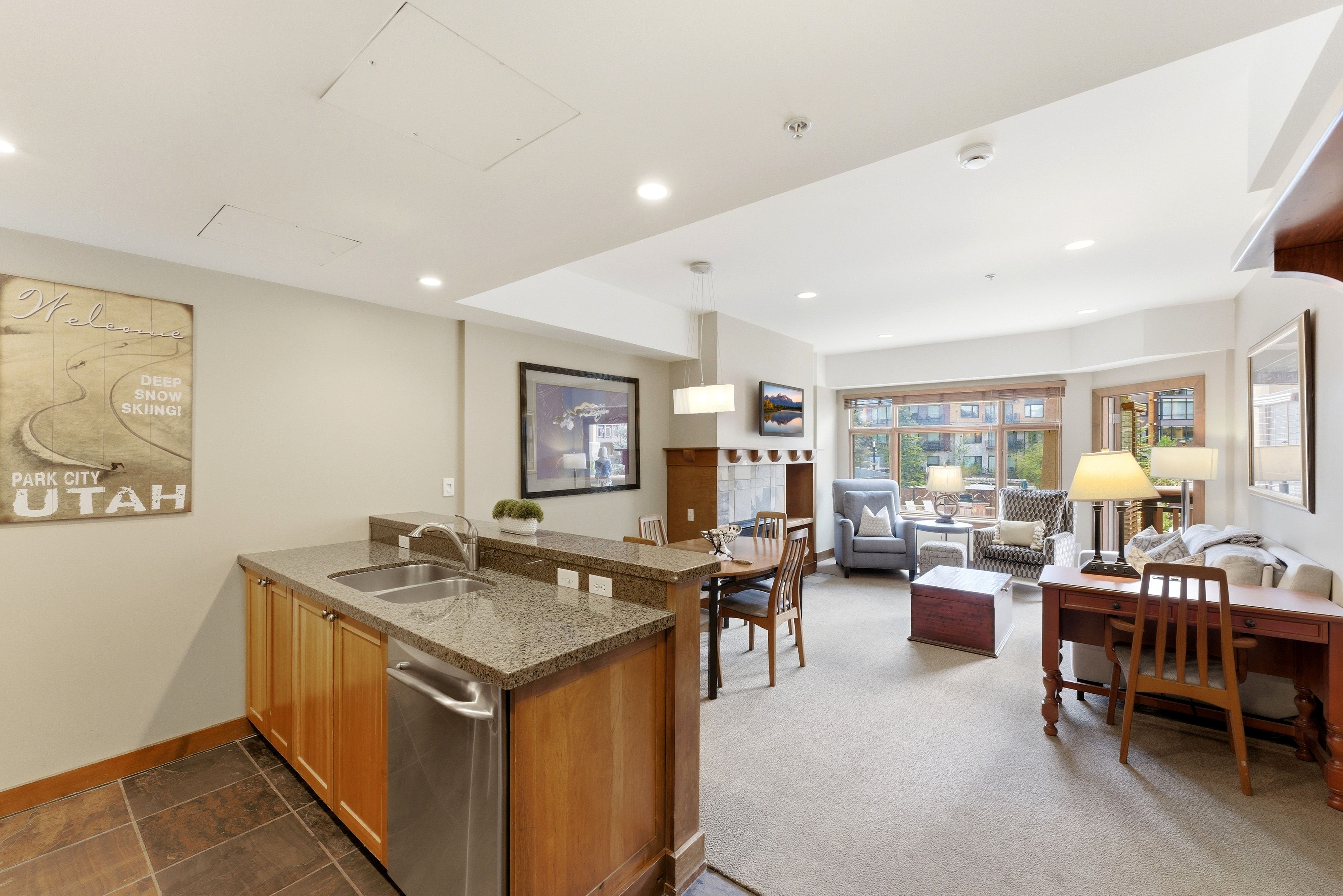 Open-concept living area featuring a kitchen island with dual sinks and stainless steel appliances, a dining space, and a living room with an integrated television