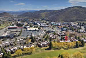 Aerial overview showcasing a golf course perimeter, a collection of residential townhomes, and a commercial district with a large parking area