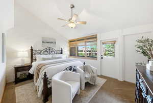 Room featuring a vaulted ceiling with a ceiling fan, white painted brick wall, and wood-framed windows