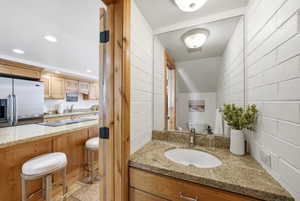 Powder room featuring a corner vanity with a granite countertop, undermount sink, and a large wall-mounted mirror