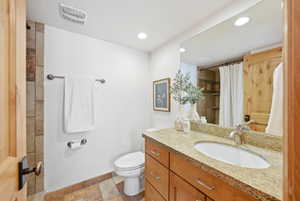 Bathroom featuring a light-toned vanity with an undermount sink, a granite-finish countertop, and wood-finish cabinetry