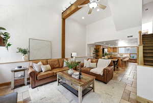 Vaulted ceiling living space featuring a white brick accent wall and exposed wood beam