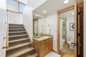 Carpeted staircase with natural wood handrail leading to a brightly lit upper level