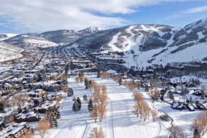 Expansive winter landscape featuring snow-covered mountain ranges and a valley with a town