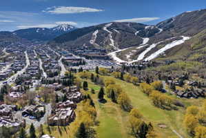 Expansive aerial encompassing a townscape, a golf course, and mountain terrain