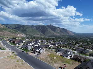 Expansive mountain backdrop with a residential community featuring a paved road and multiple single-family homes