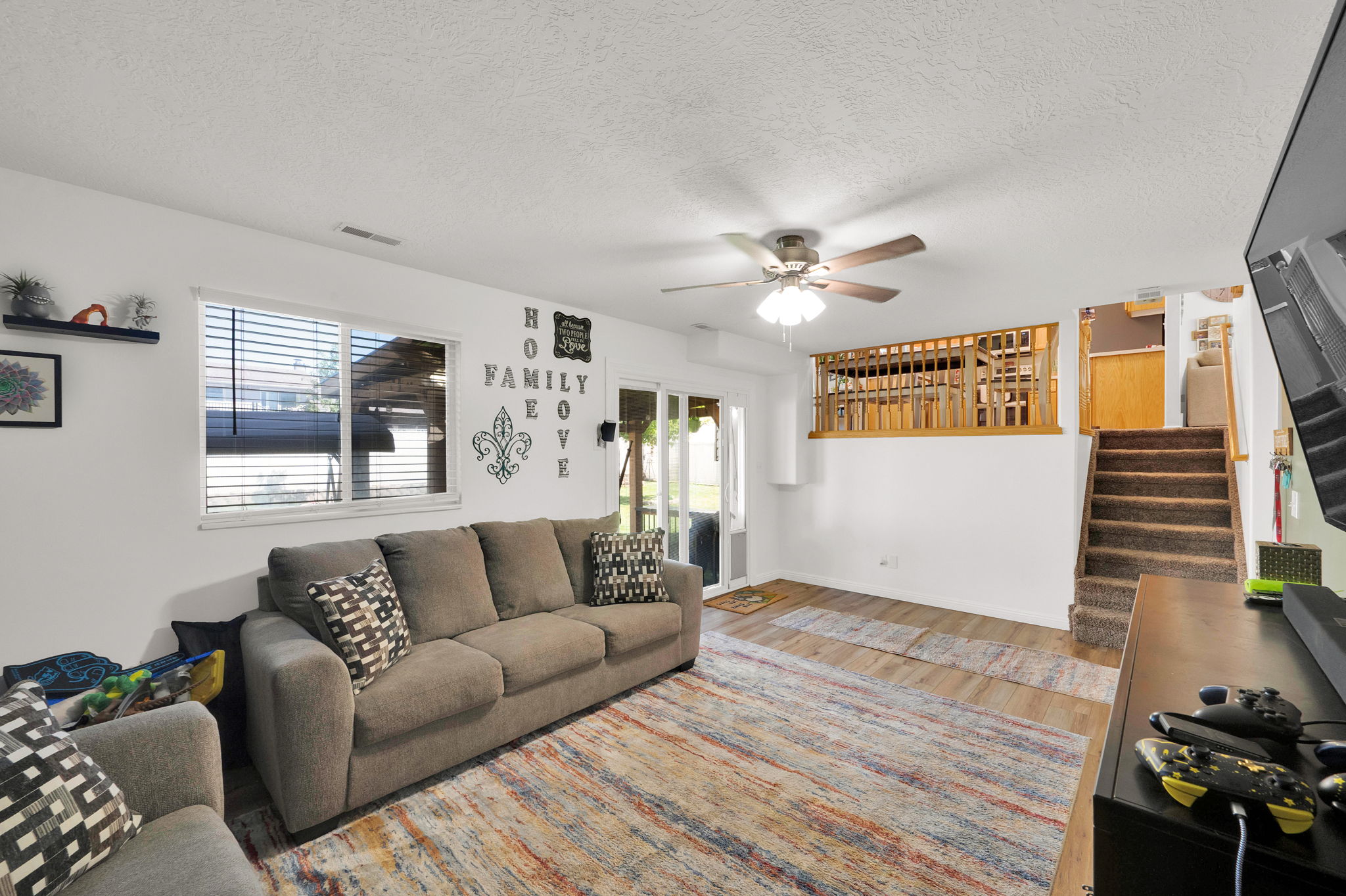 Spacious living area featuring wood-finish flooring and a ceiling fan