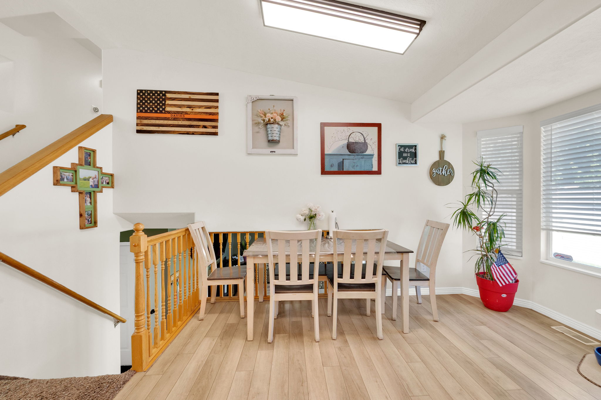 Dining area featuring light wood-finish flooring, white walls, and a large window with blinds