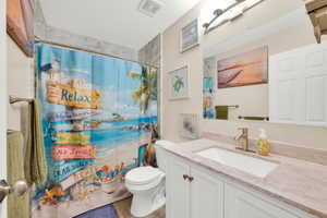 Bathroom featuring a single vanity with a rectangular sink, a light-toned countertop, and white cabinetry