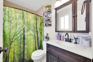 Bathroom featuring a dark wood-finish vanity with a white countertop and oval under-mount sink