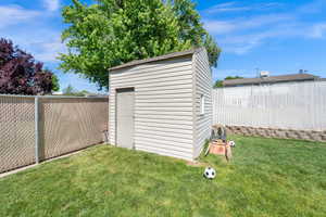 Backyard featuring a functional storage shed with horizontal siding, a side entry door, and a small window
