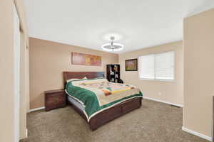 Bedroom featuring neutral wall paint, textured carpet flooring, and a window with horizontal blinds