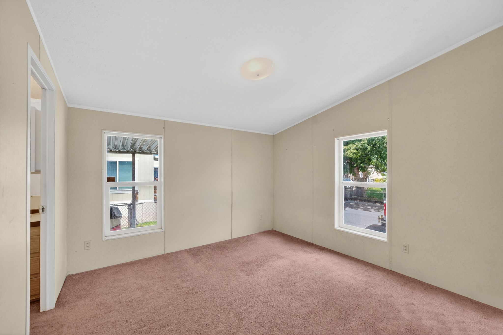 Carpeted room featuring two windows, pale beige walls, white trim, and a ceiling light fixture
