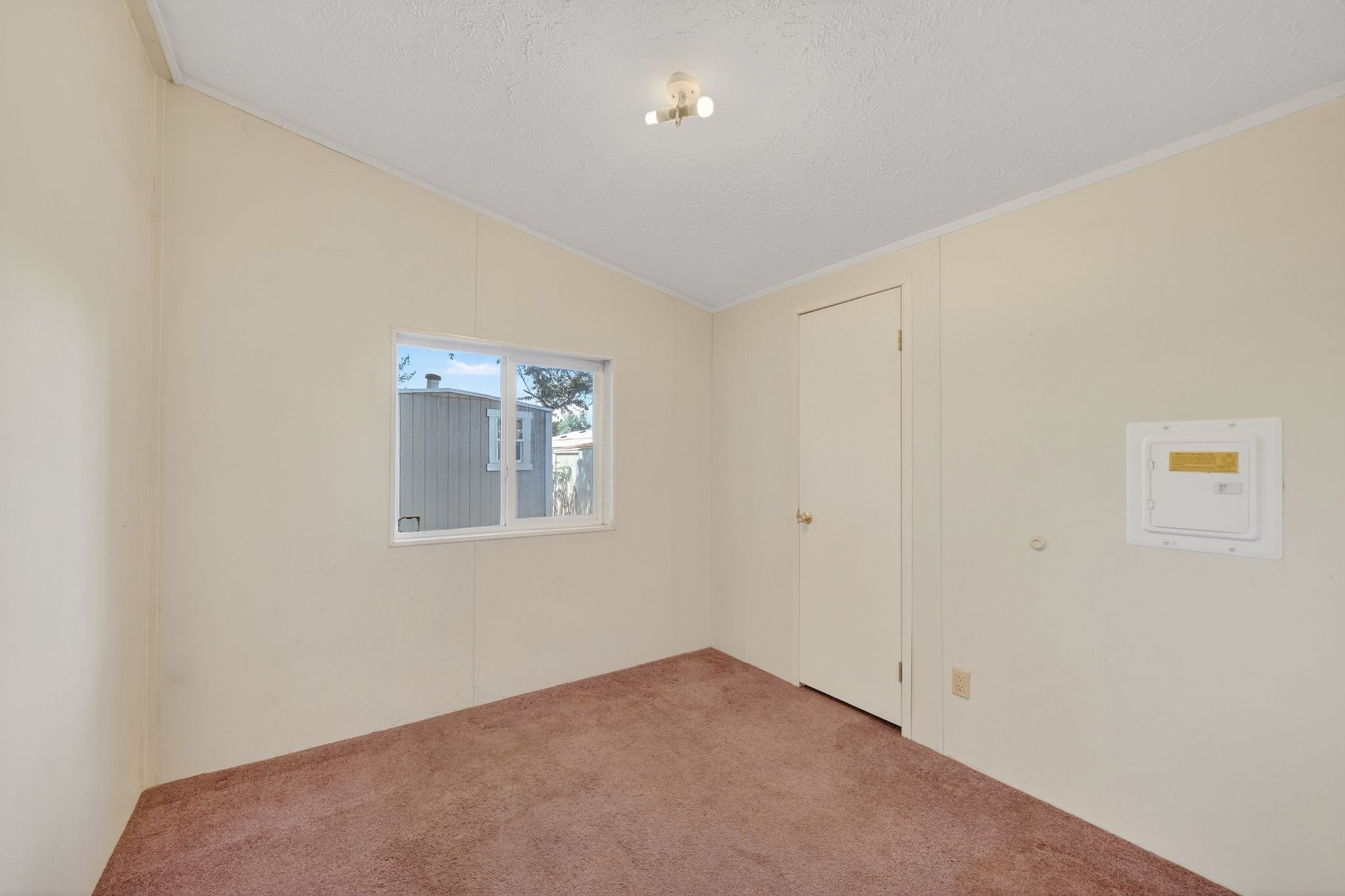 Room with a window, single door, and brown carpet flooring