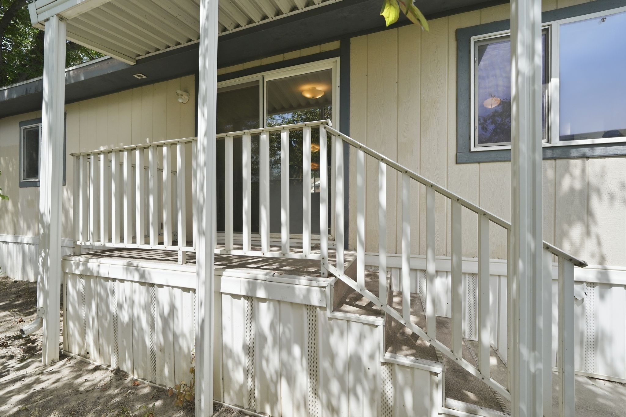 Exterior decking with railing and steps, featuring a covered patio area with vertical supports