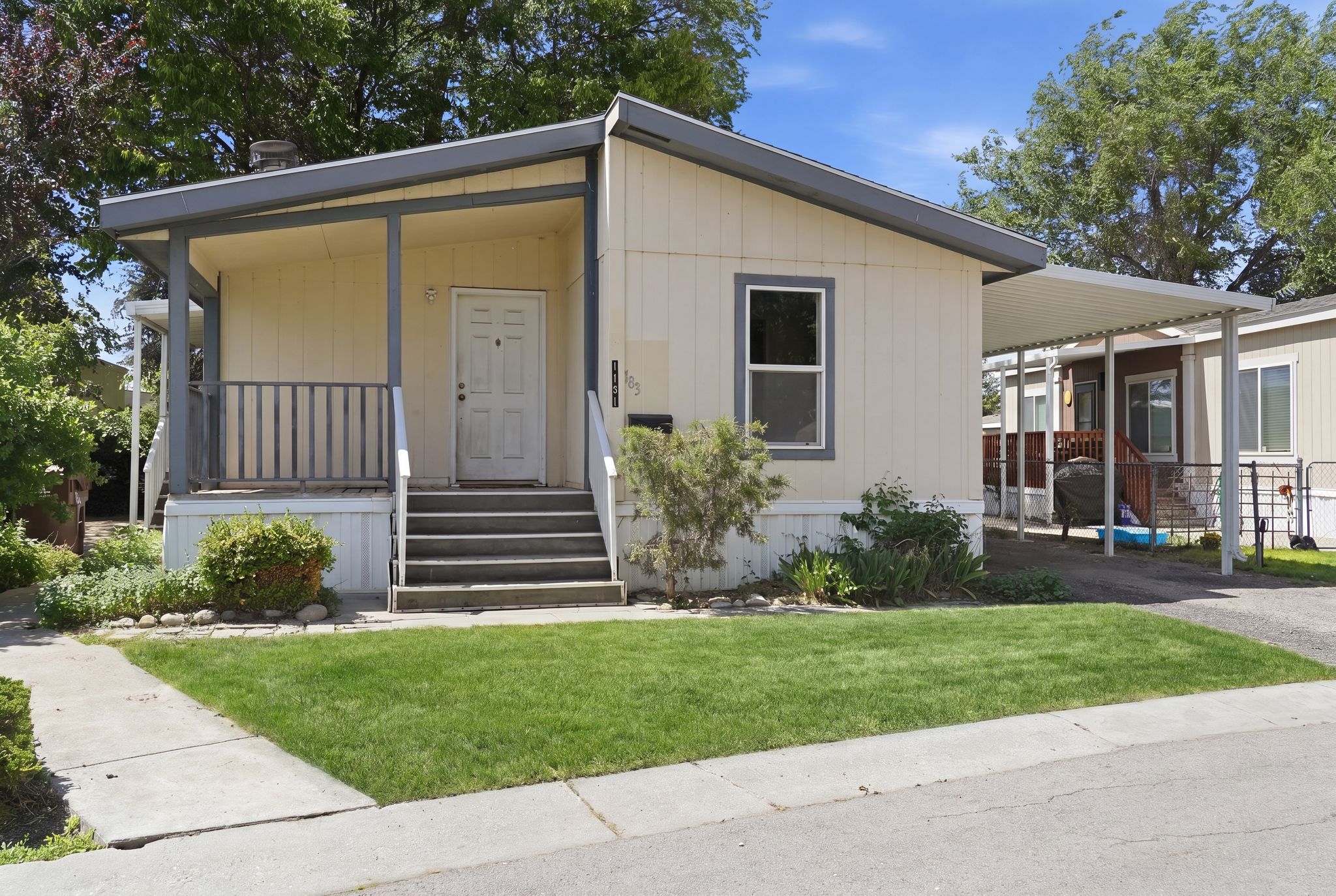 Single-story home featuring a covered front porch, a dedicated carport, established front yard landscaping, and a sidewalk leading to the front entry